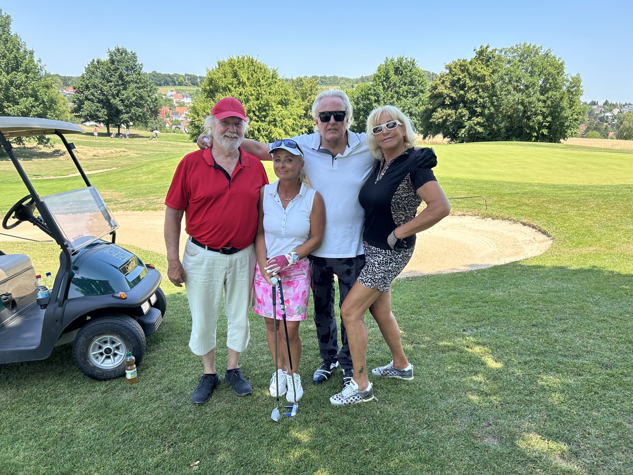 Vierer-Flight neben Golfcart und Bunker an einem Sommertag
