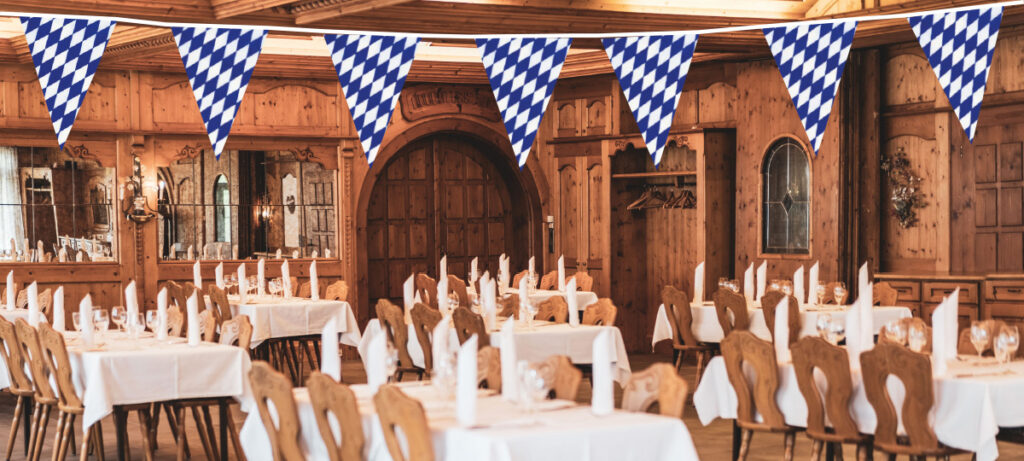 Festsaal mit weiß-blauen Wimpeln und gedeckten Tischen