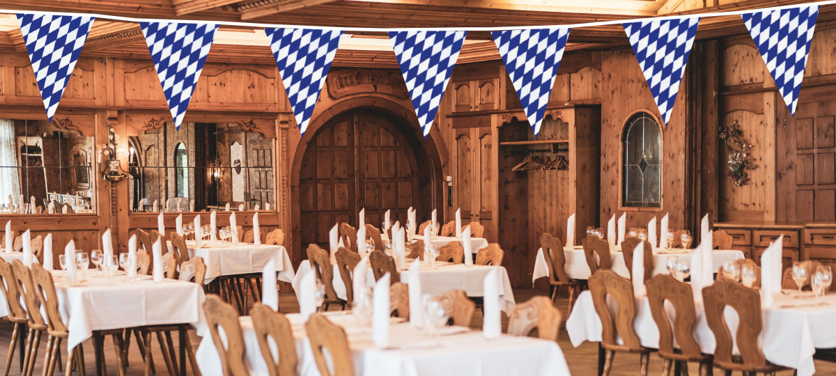 Festsaal mit weiß-blauen Wimpeln und gedeckten Tischen