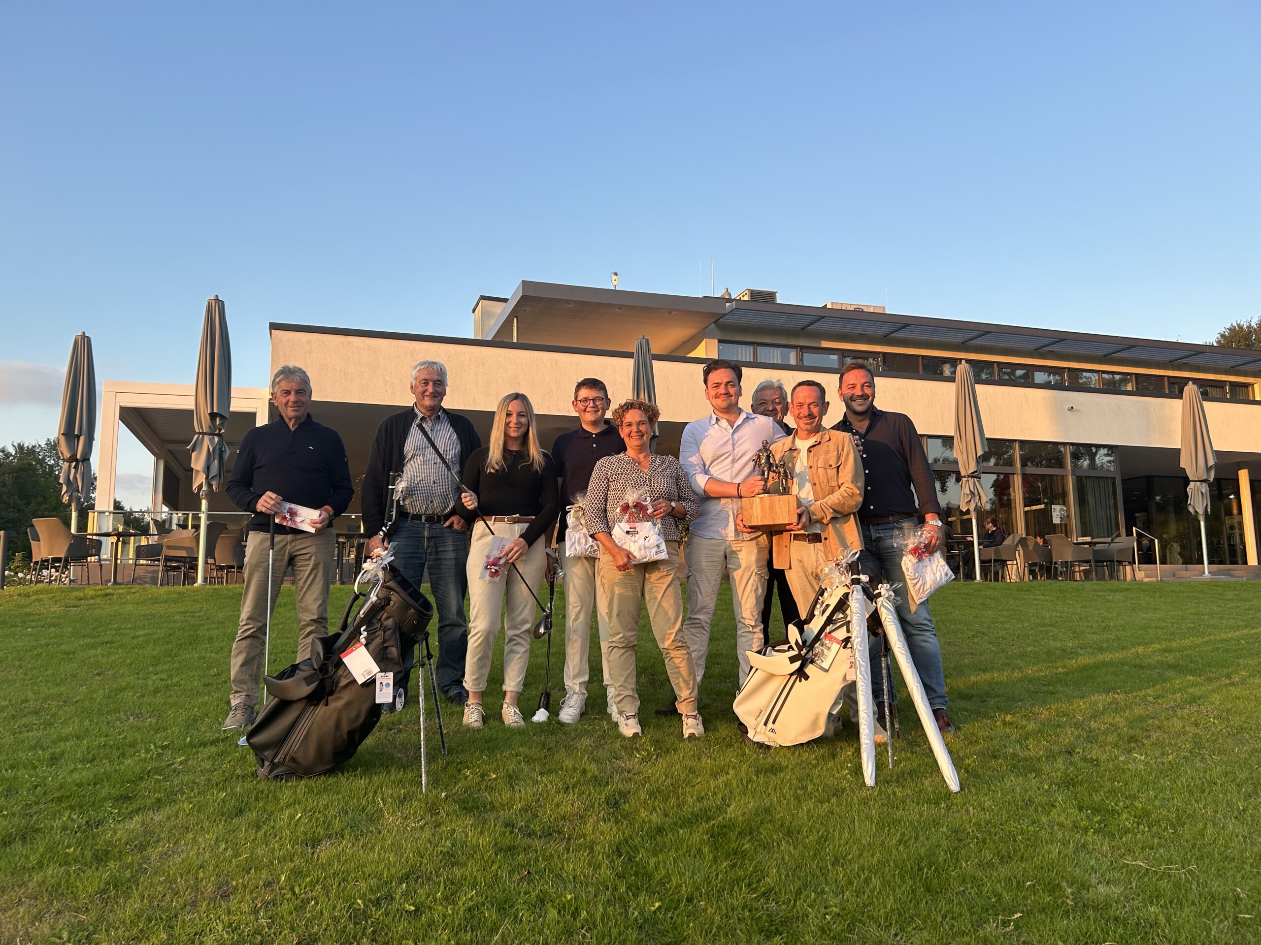 Teilnehmende des Family Cups mit Preisen vor dem Clubhaus im Abendlicht