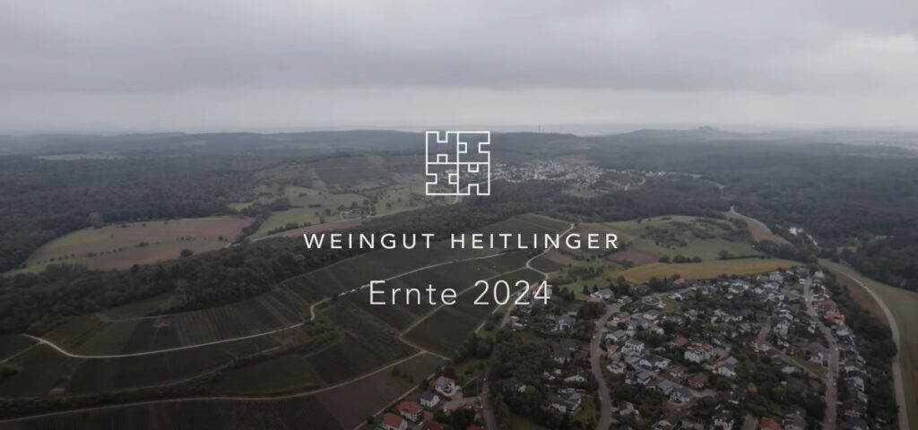 Titelbild „Weingut Heitlinger – Ernte 2024“ über Luftbild von Weinbergen und Ort