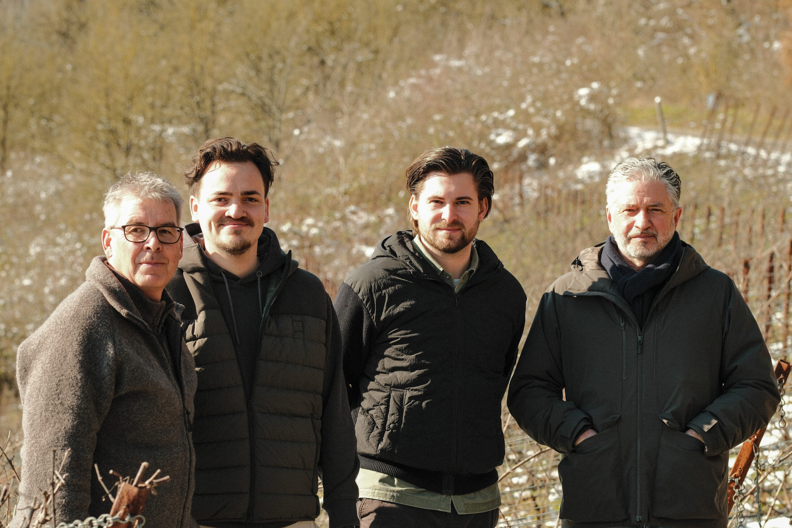 Vier Männer in Winterjacken im Weinberg