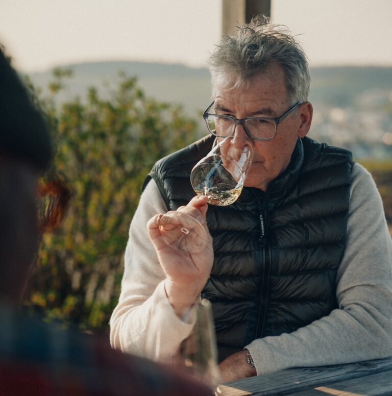 Mann mit Brille riecht konzentriert an einem Glas Weißwein