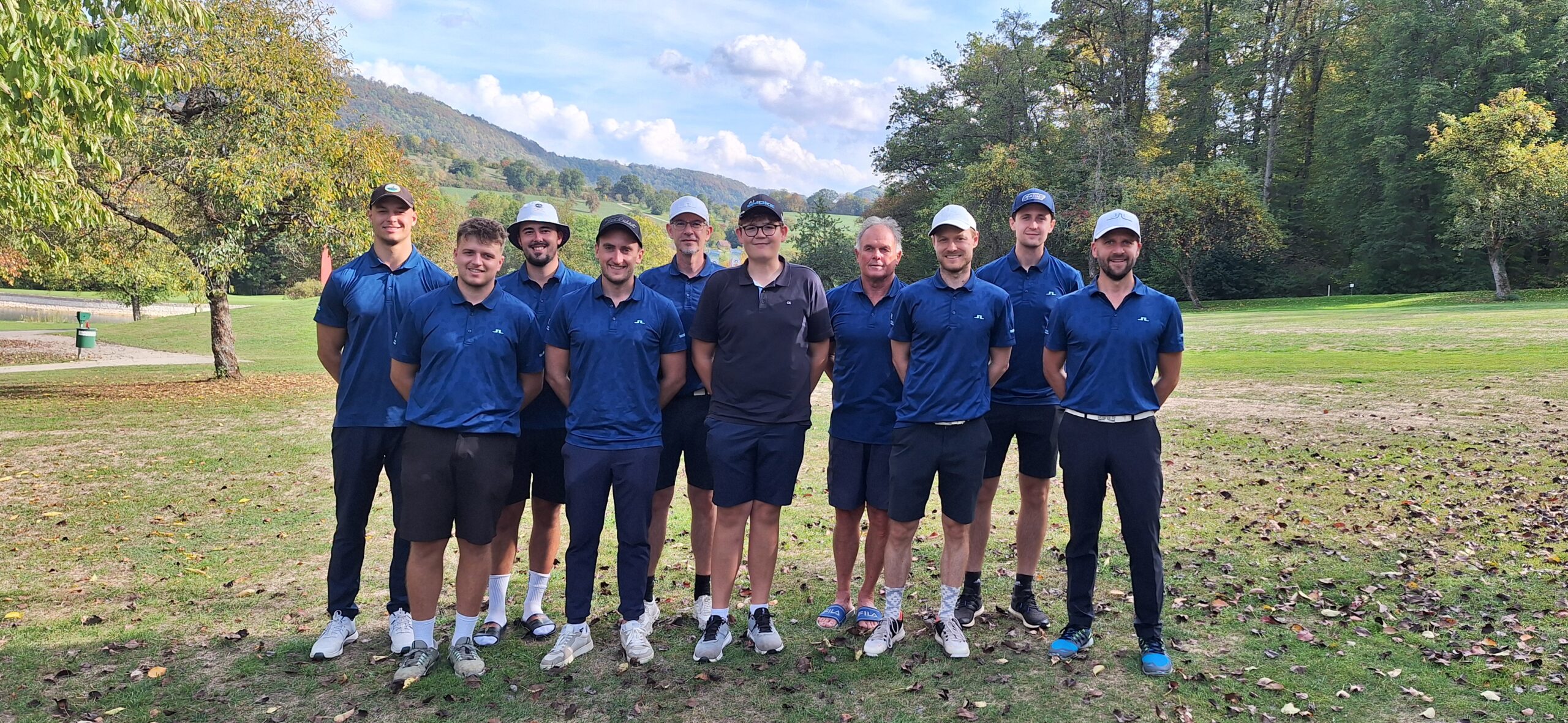Golf-Mannschaft des Heitlinger Golf Resorts in blauen Poloshirts auf dem Fairway, Hügel im Hintergrund